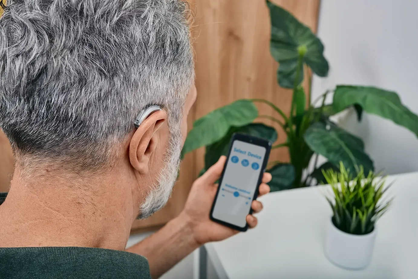 homme-reglant-son-appareil-auditif-avec-une-application-sur-son-smartphone